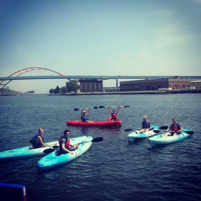 A group of kayakers in single kayaks smiling on Lake Michigan