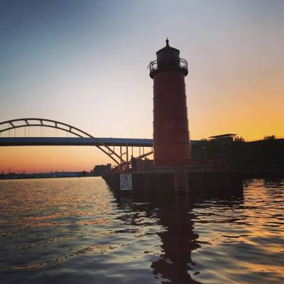 Gold sunset behind a red light house and huge yellow bridge
