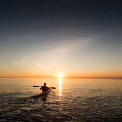 A kayaker peering into the sunset on Lake Michigan