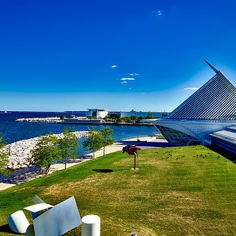 Lake meeting green pastures and a steel angular building