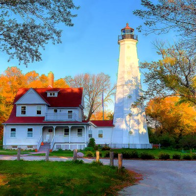 A white lighthouse with a red rooftop in front of fall foliage trees